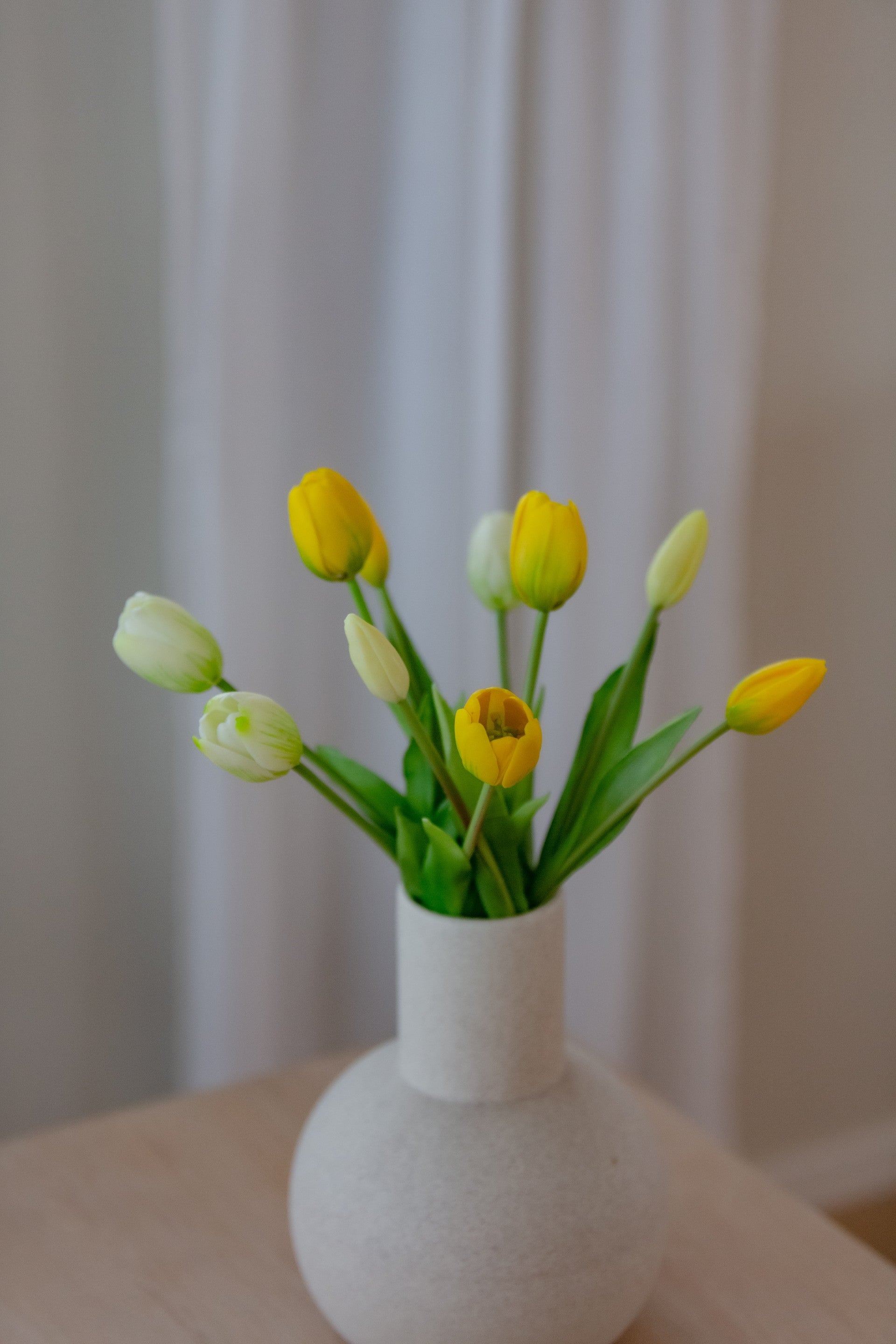 Kunstig blomsterbukett i gule toner på bord