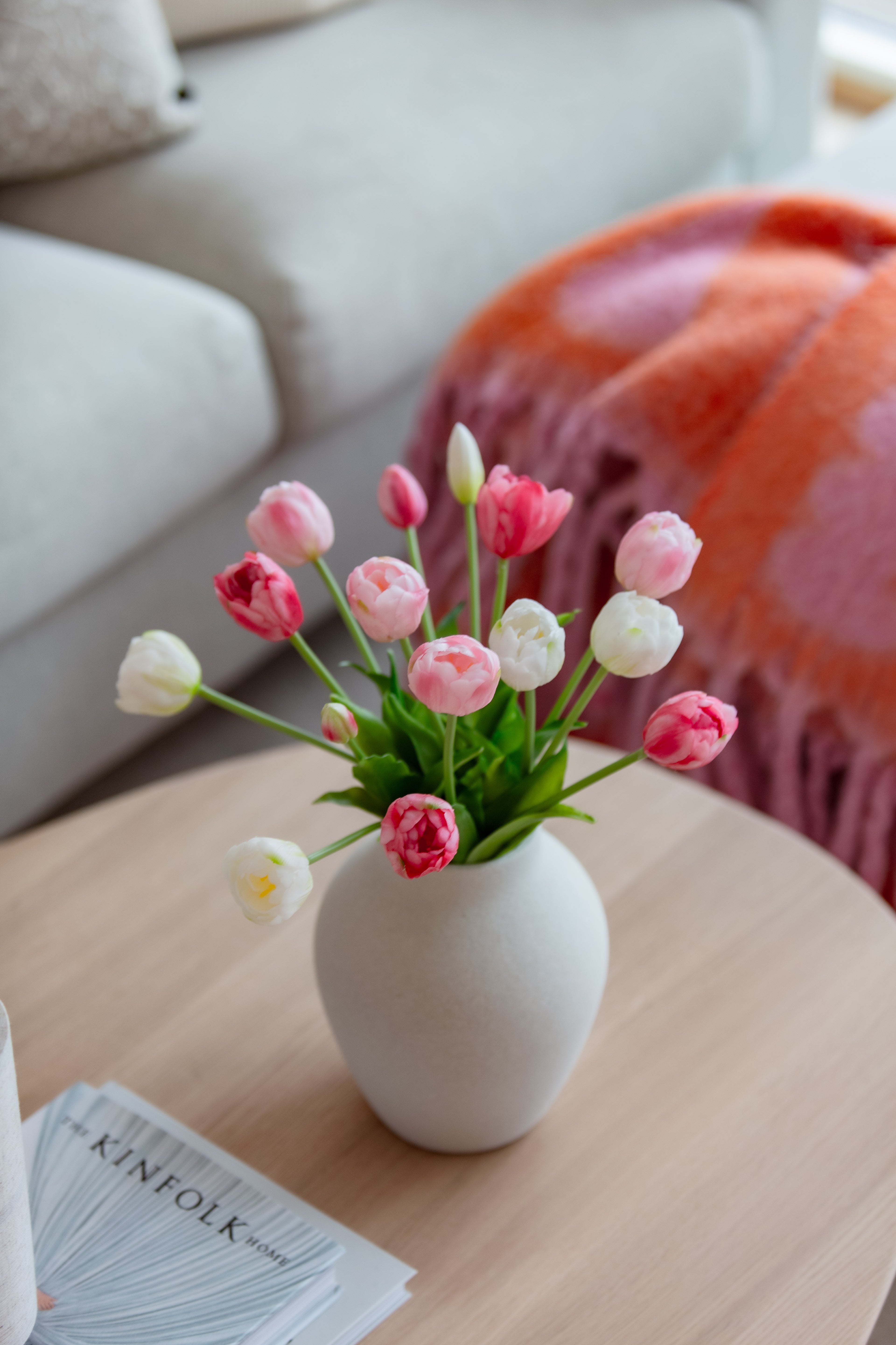 Kunstig blomsterbukett i rosa toner på sofabord