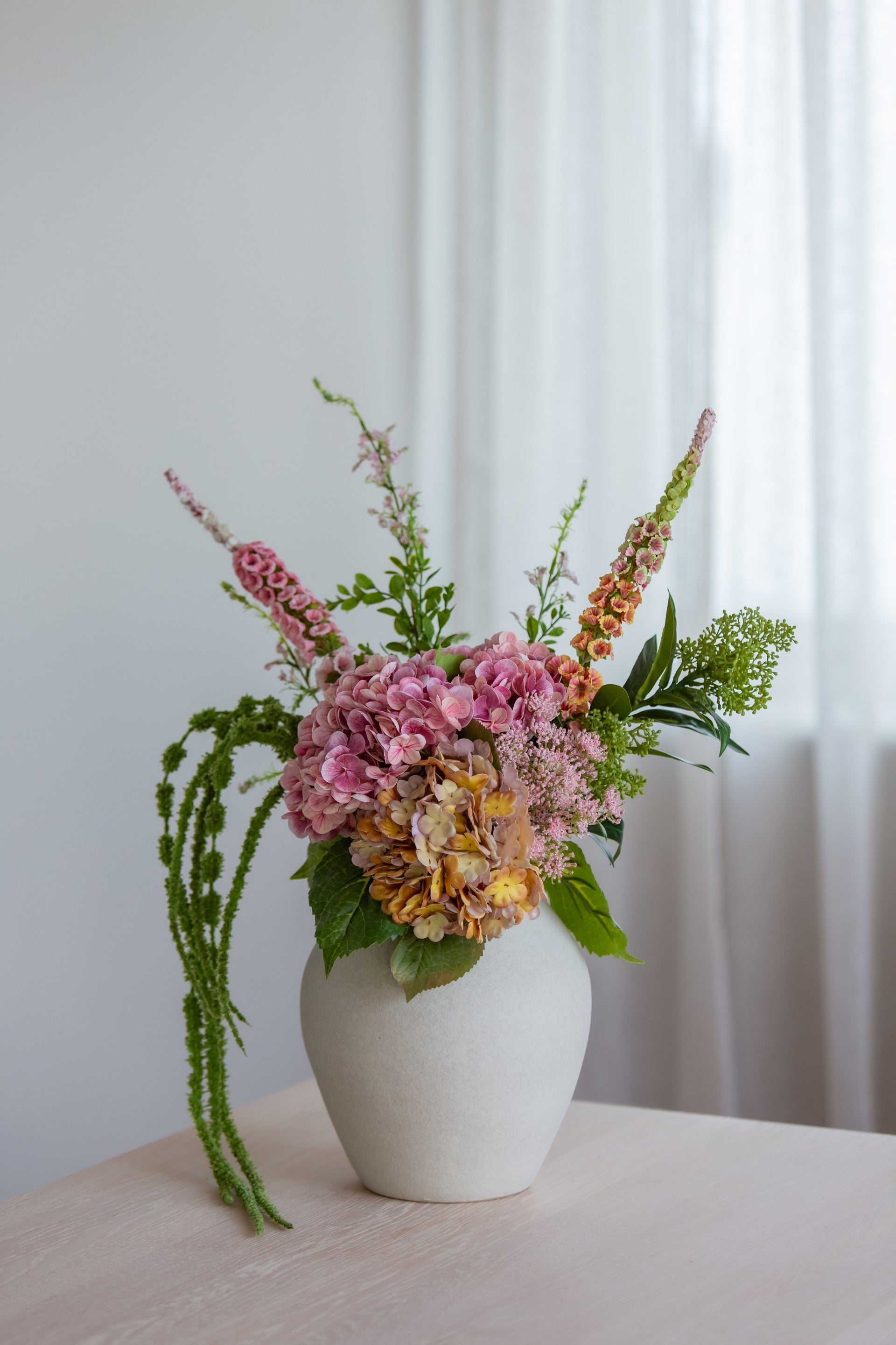 Kunstig bukett med rosa og oransje blomster i vase