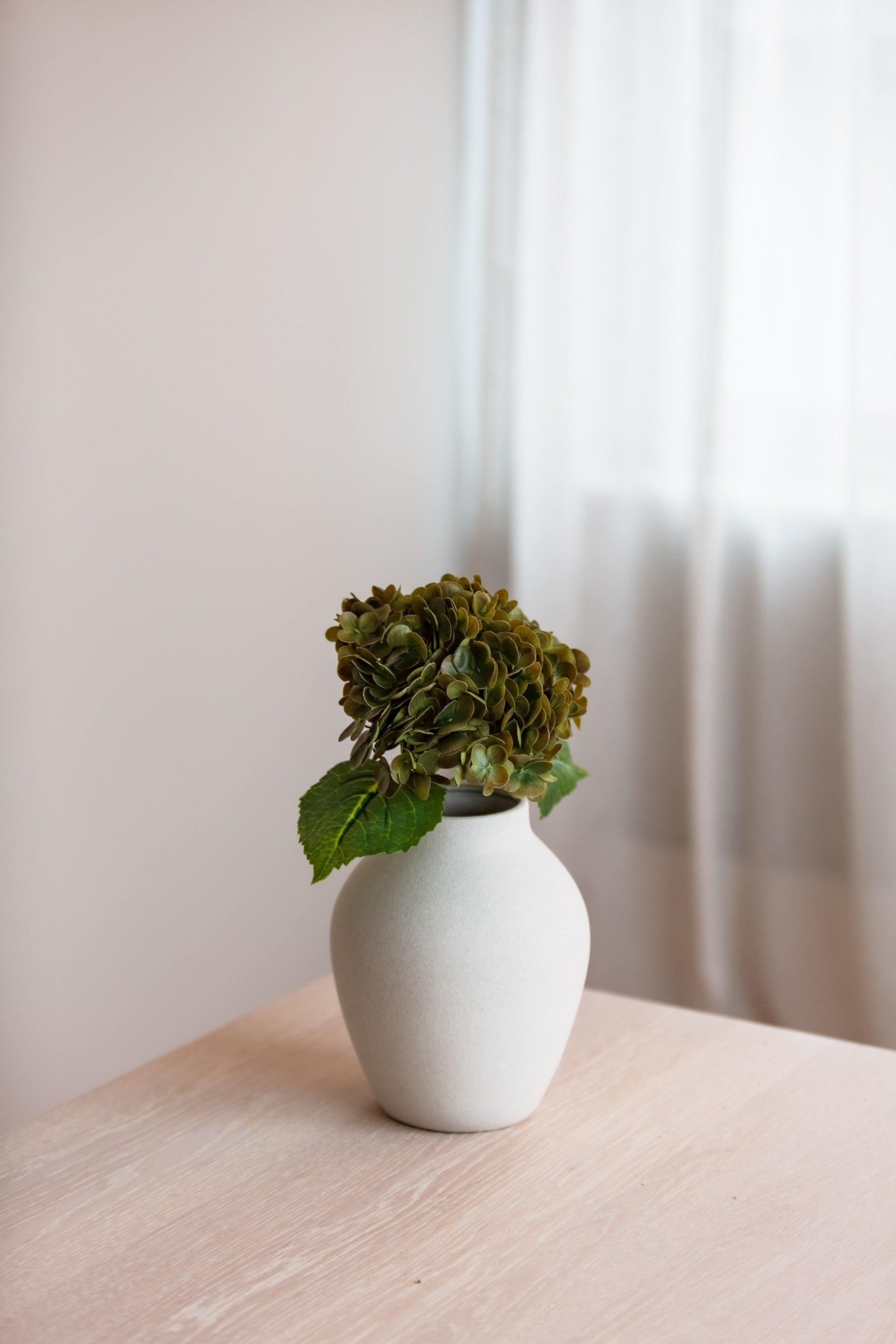 Kunstig olivengrønn blomst brukt som dekorasjon i vase