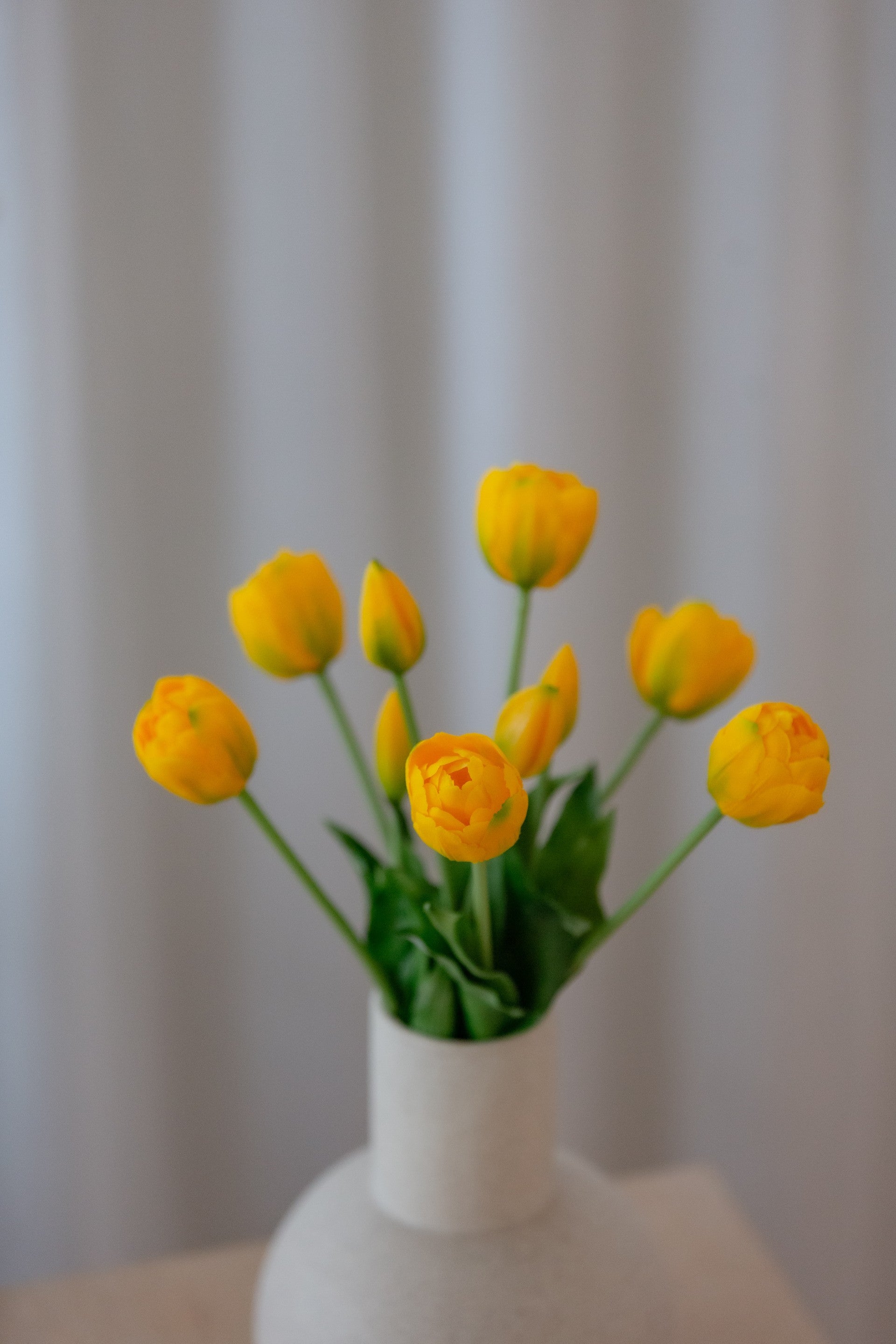 Kunstige gule tulipaner i bukett med vase