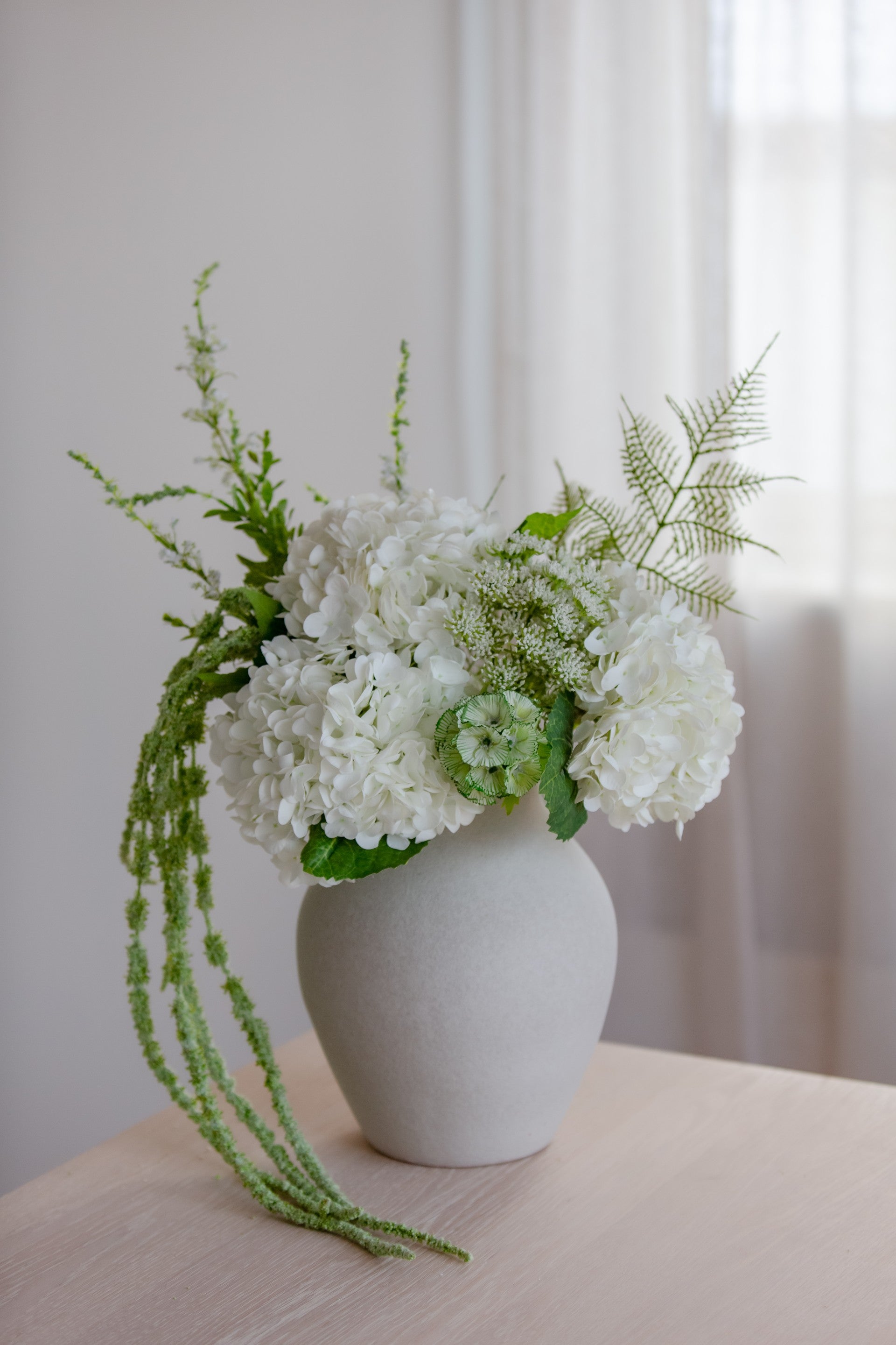 Hvit bukett av kunstige blomster i rund vase