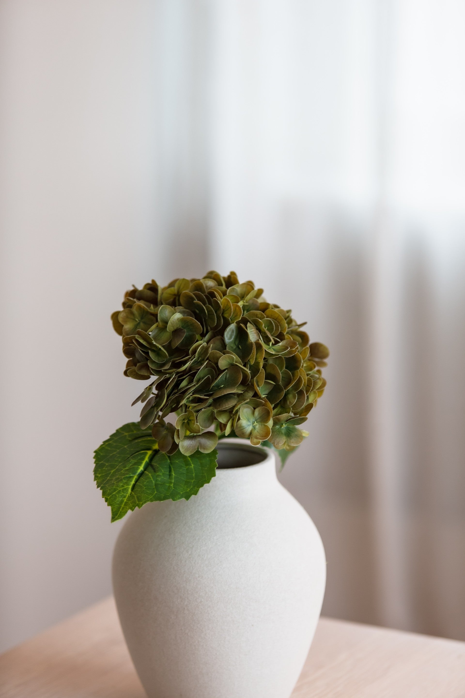 Kunstig hydrangea stilk i olivengrønn nyanse i vase